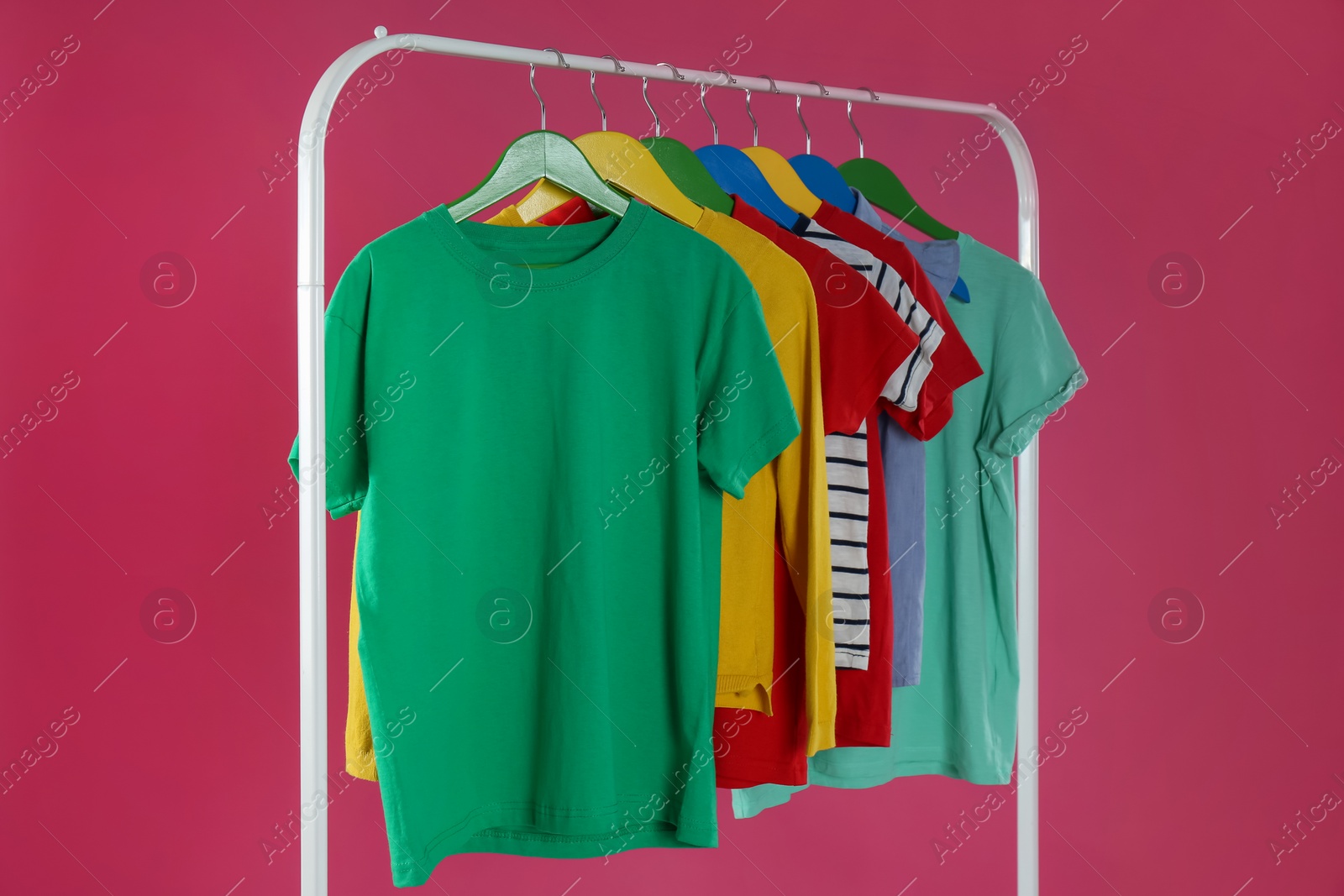 Photo of Rack with stylish children clothes on pink background