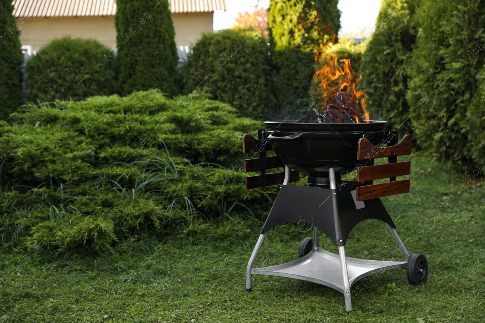 Photo of Portable barbecue grill with fire flames outdoors. Space for text