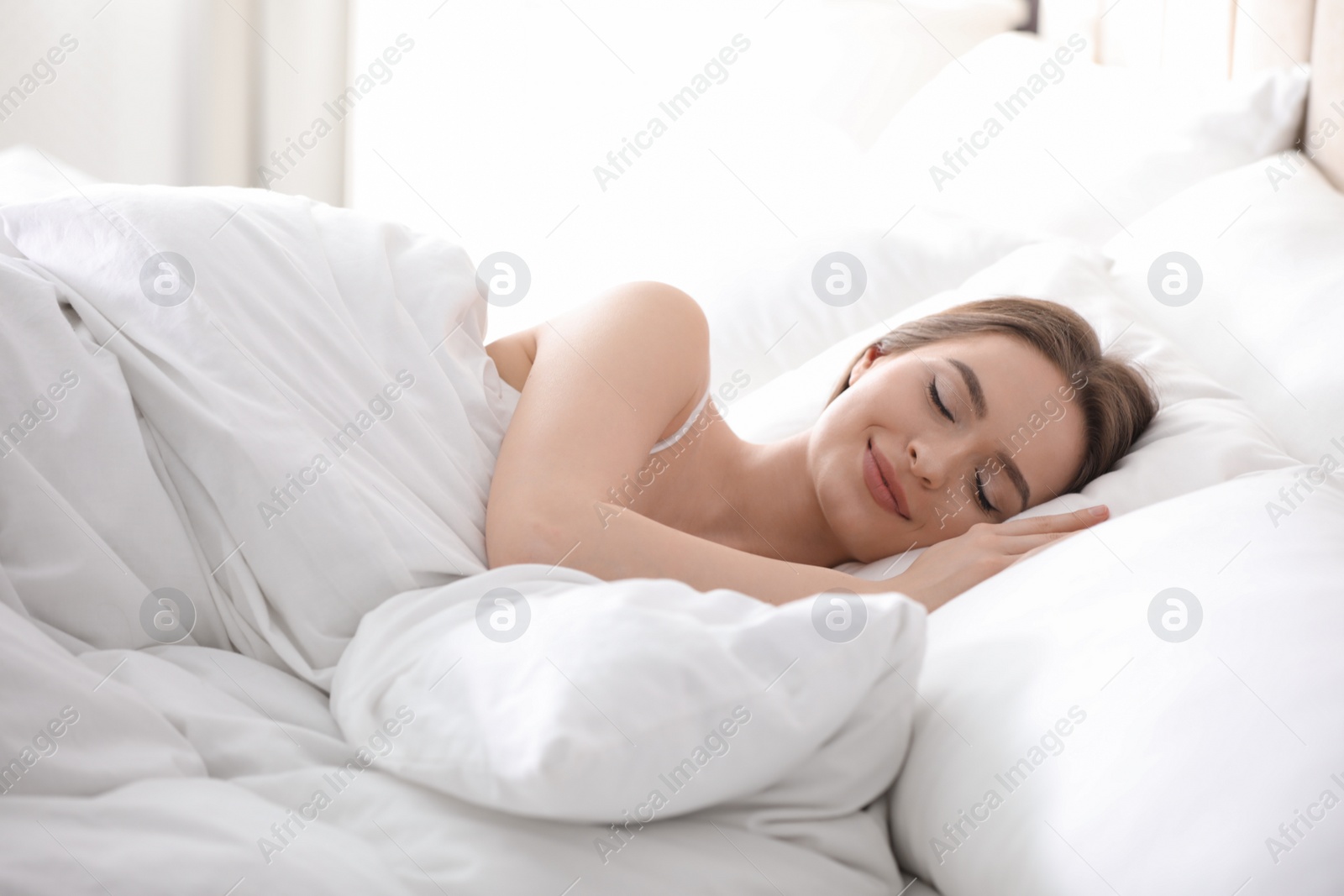 Photo of Young woman sleeping on comfortable pillow in bed at home