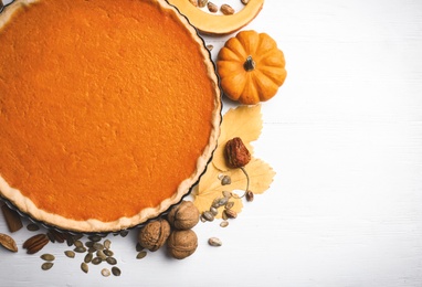 Photo of Flat lay composition with delicious homemade pumpkin pie on white wooden table. Space for text
