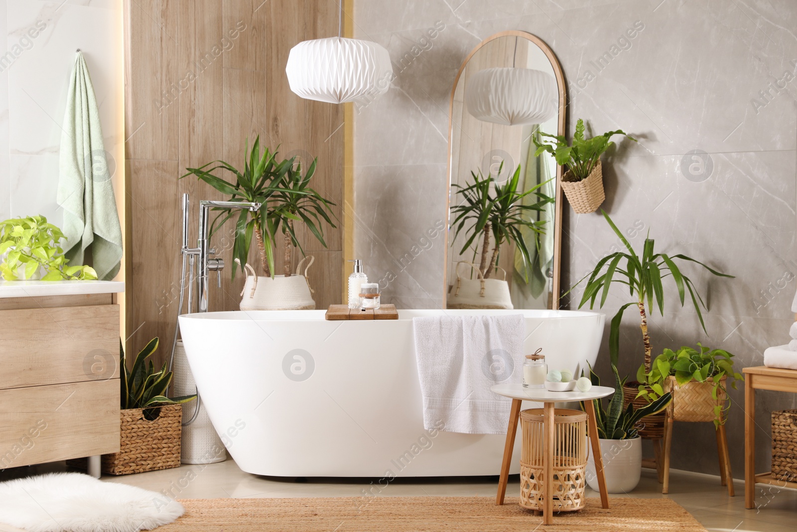 Photo of Modern white tub and beautiful green houseplants in bathroom. Interior design