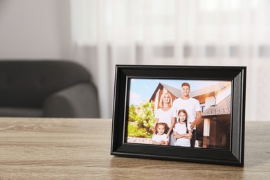 Photo of Pleasant memories. Black photo frame with family portrait on wooden table indoors. Space for text