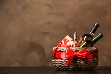 Photo of Gift basket with bottles of wine on dark background. Space for text