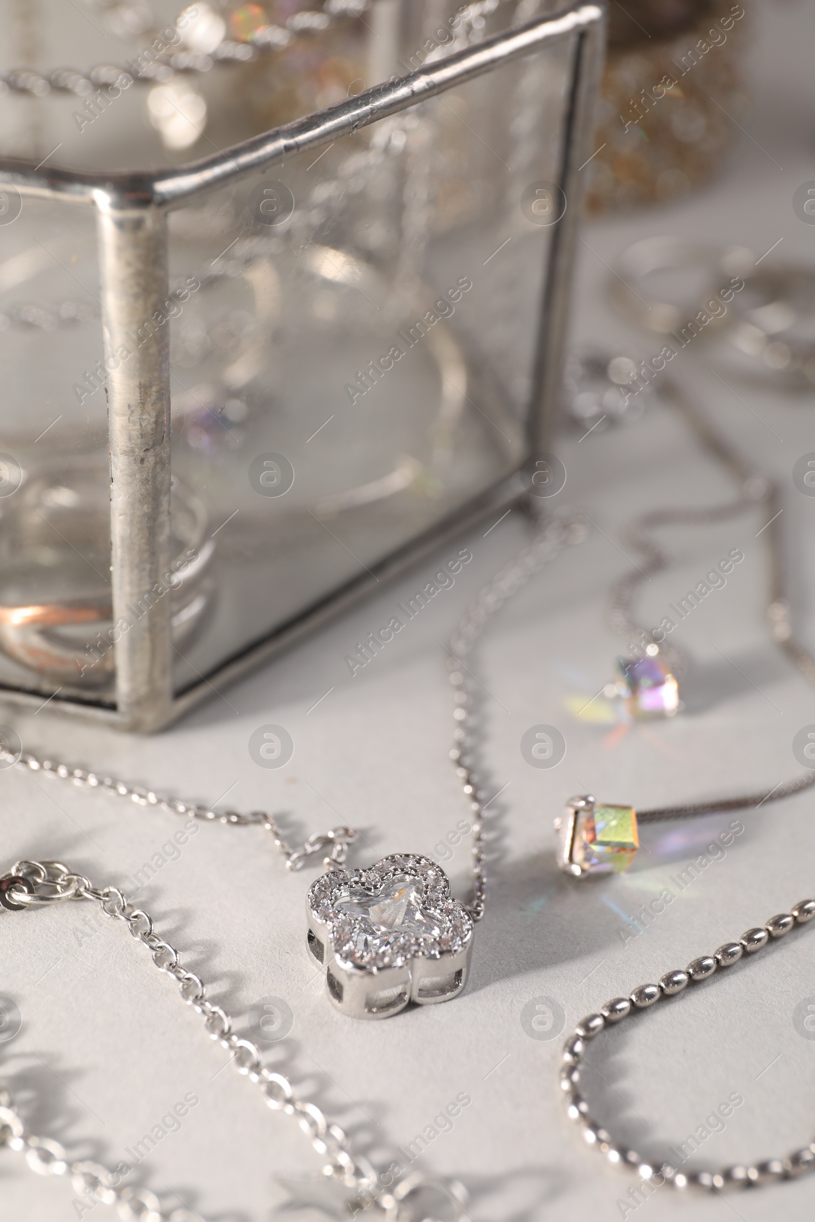 Photo of Different metal chains and stylish earrings on light table, closeup. Luxury jewelry