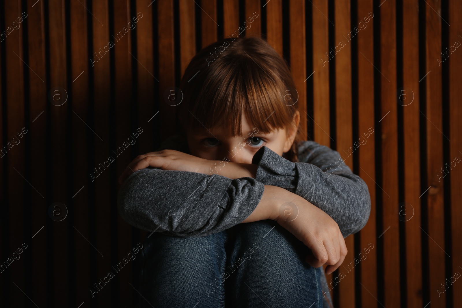 Photo of Sad little girl on wooden background. Child in danger