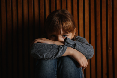 Sad little girl on wooden background. Child in danger