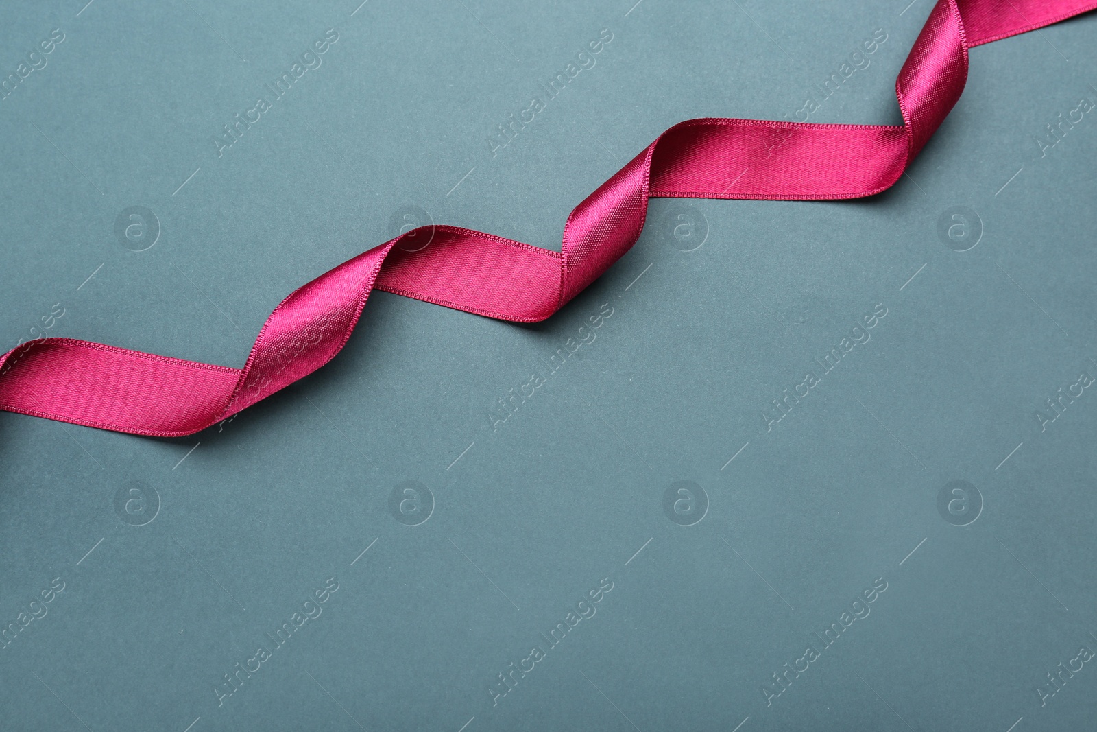 Photo of Beautiful pink ribbon on grey background, top view. Space for text