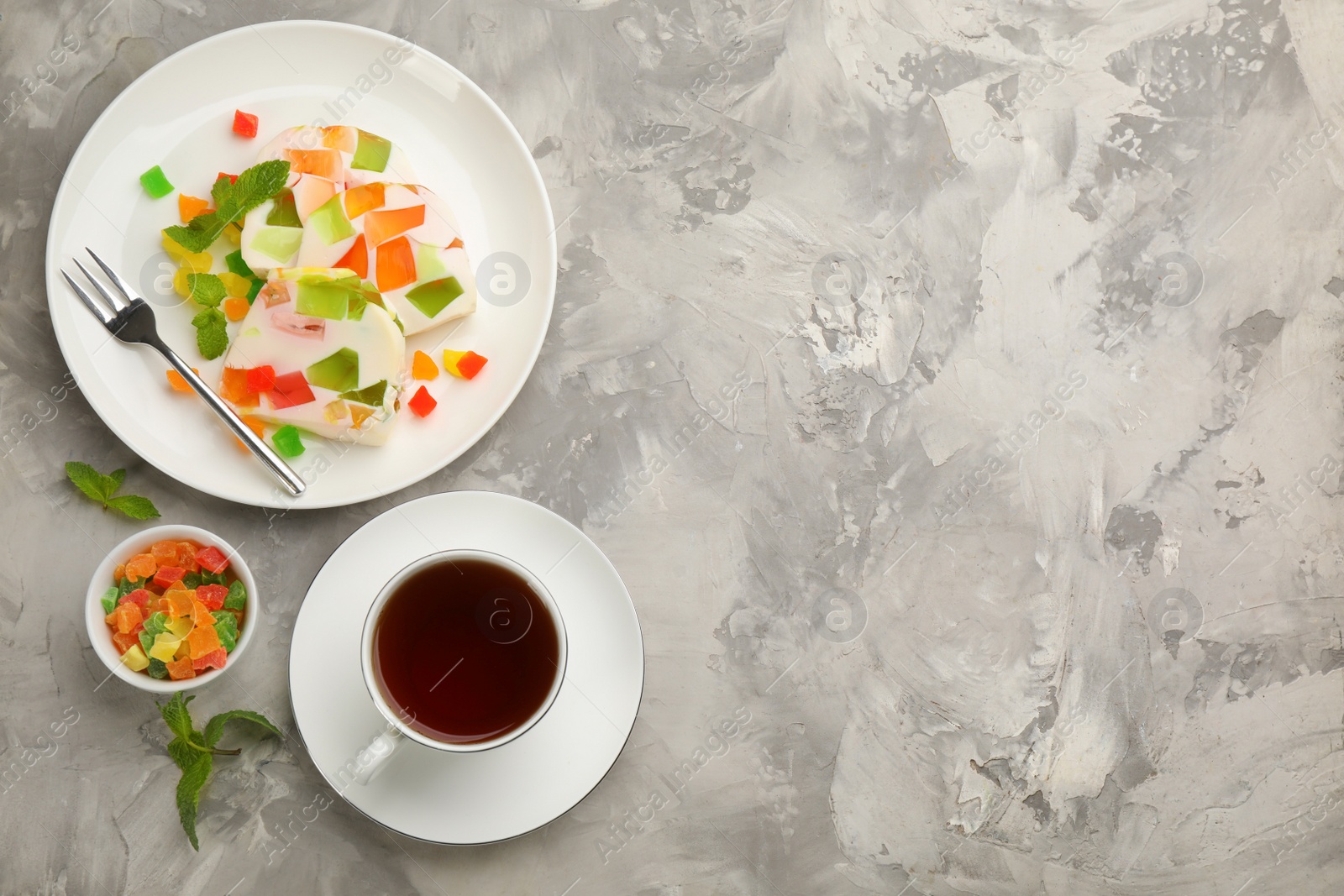 Photo of Delicious broken glass jelly dessert on white marble table, flat lay. Space for text