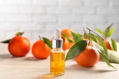 Bottle of tangerine essential oil and fresh fruits on white wooden table
