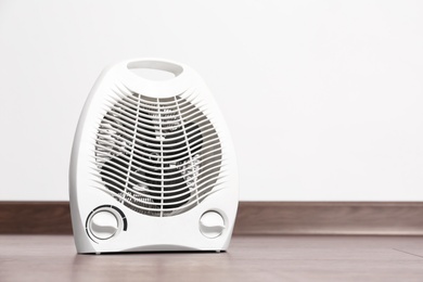 Photo of Modern electric fan heater on floor in room, space for text