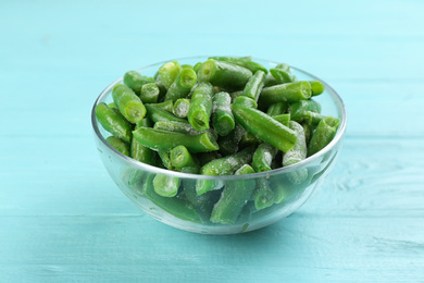 Photo of Frozen cut green beans on light blue wooden table. Vegetable preservation