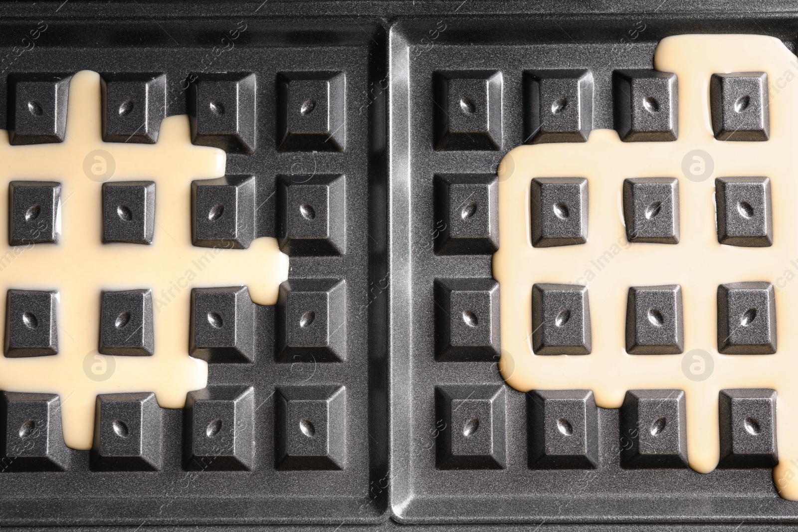 Photo of Belgian waffle maker with dough, top view