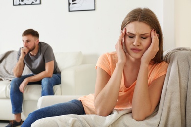 Photo of Young couple ignoring each other after argument in living room. Relationship problems