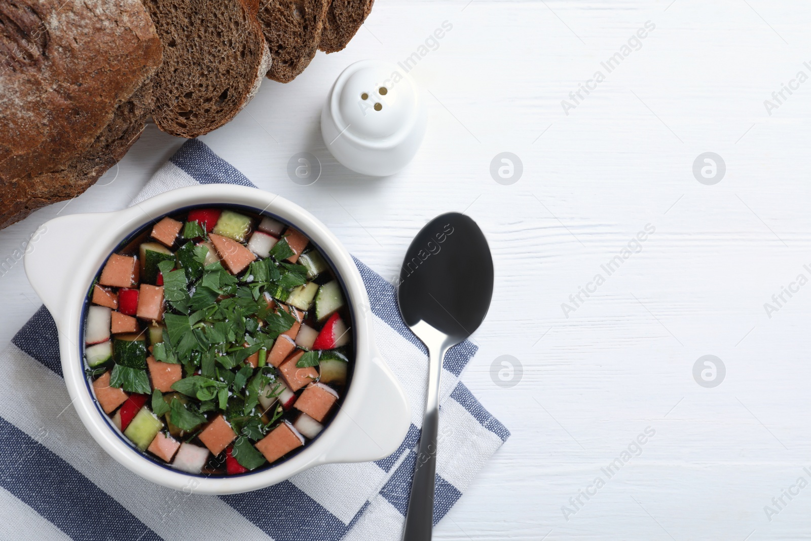 Photo of Delicious cold okroshka with kvass served on white wooden table, flat lay and  space for text. Traditional Russian summer soup