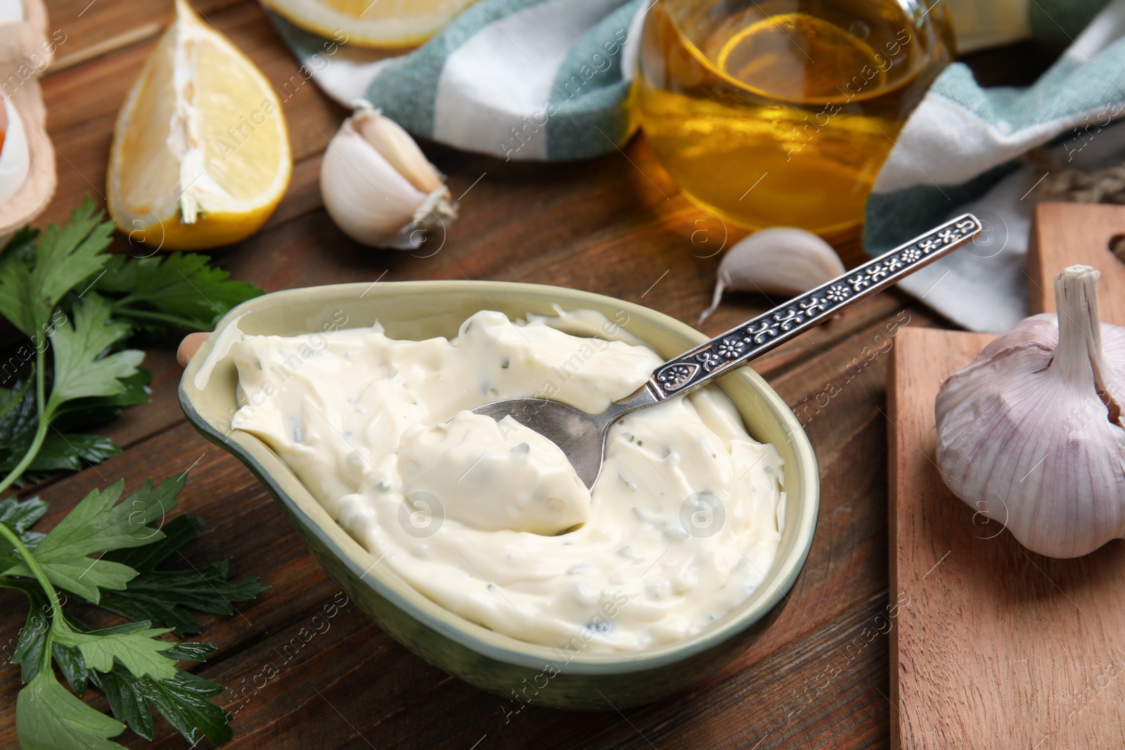 Photo of Tasty tartar sauce and ingredients on wooden table