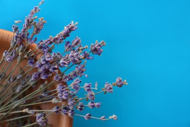 Photo of Bowl with beautiful lavender flowers on blue background, closeup . Space for text