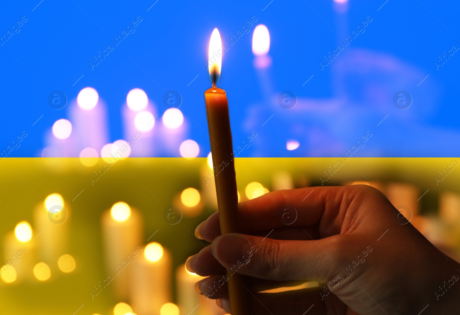 Image of Woman with candle against Ukrainian national flag, closeup