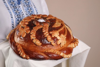 Woman with korovai on grey background, closeup. Ukrainian bread and salt welcoming tradition