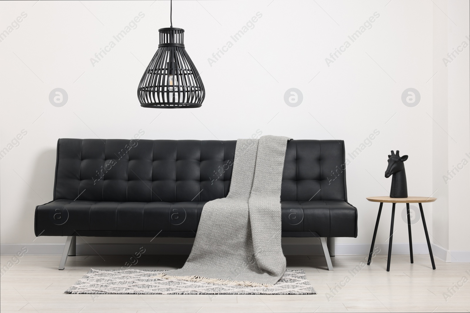 Photo of Comfortable sofa, blanket and side table in living room