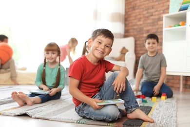 Photo of Cute child with book indoors. Learning by playing