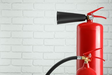 Photo of Fire extinguishers against white brick wall. Space for text