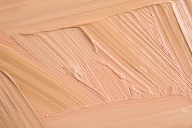 Photo of Samples of different foundation shades as background, top view