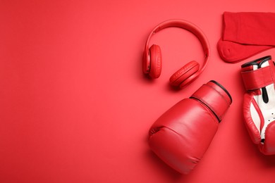 Photo of Sports equipment. Boxing gloves, headphones and socks on red background, flat lay. Space for text