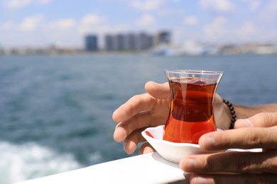 Photo of Man with glass of tea and blurred sea on background, closeup