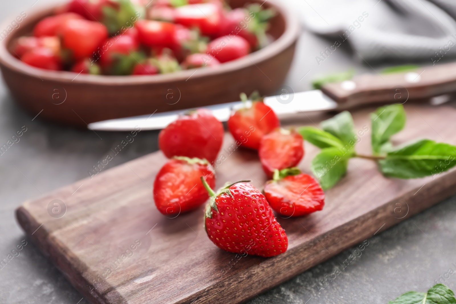 Photo of Wooden board with ripe red strawberries on table