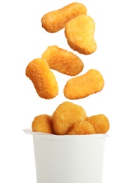 Fresh chicken nuggets falling into container on white background