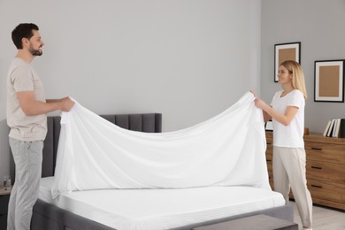 Couple changing bed linens in room. Domestic chores