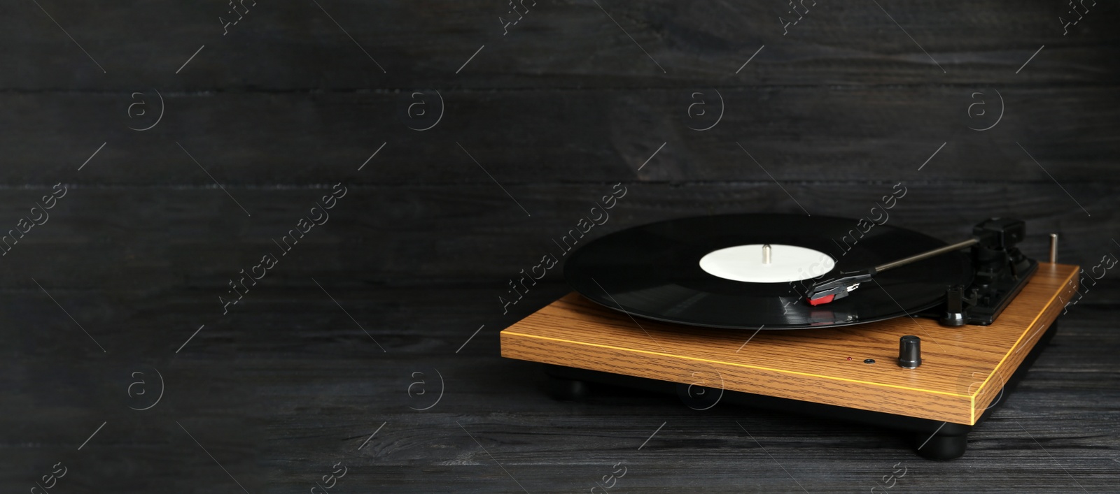 Photo of Turntable with vinyl record on black wooden background. Space for text