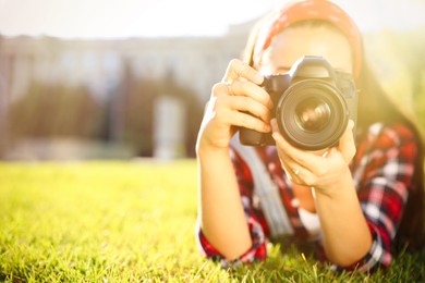 Image of Photographer taking picture with professional camera on green grass. Space for text