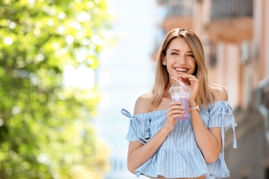 Photo of Young woman with plastic cup of healthy smoothie outdoors