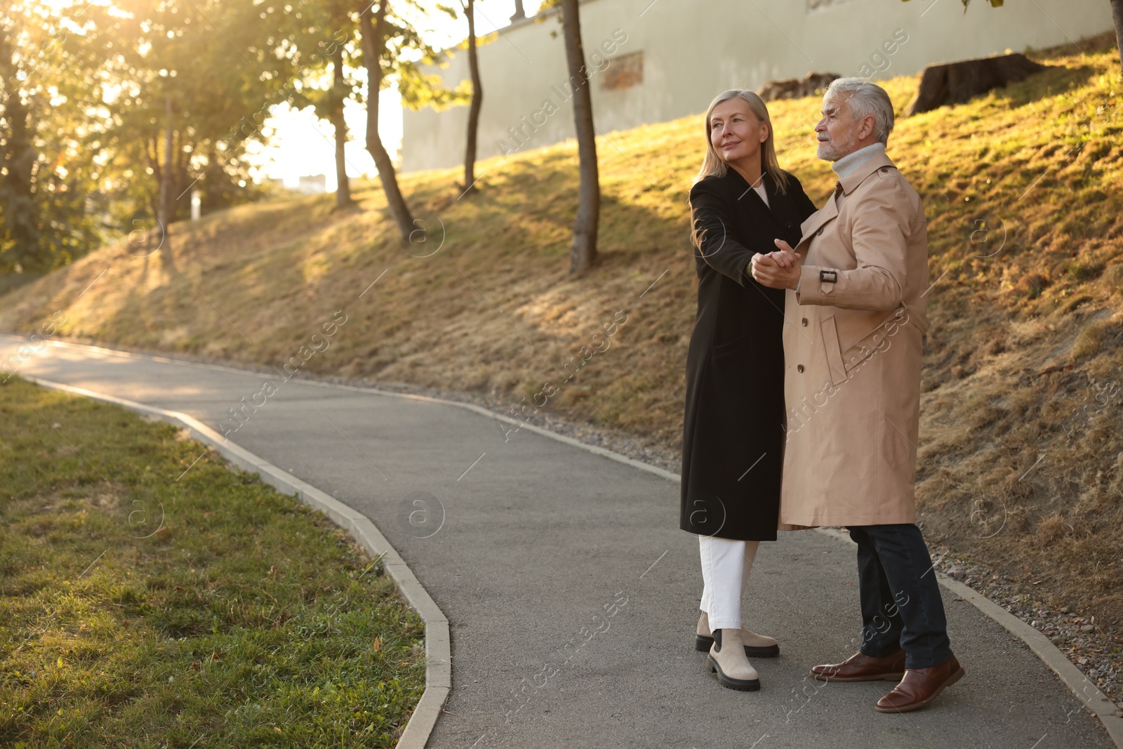 Photo of Affectionate senior couple dancing together outdoors, space for text