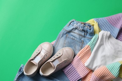 Stylish child clothes and shoes on green background, flat lay. Space for text