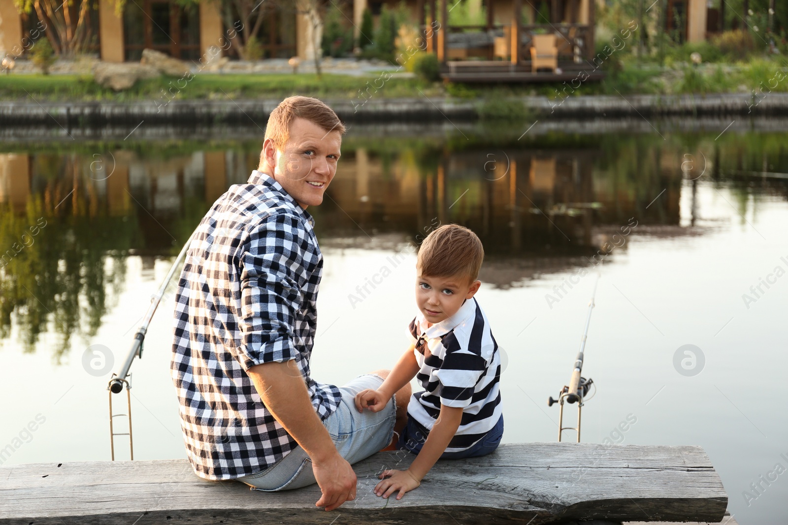 Photo of Dad and son fishing together on sunny day