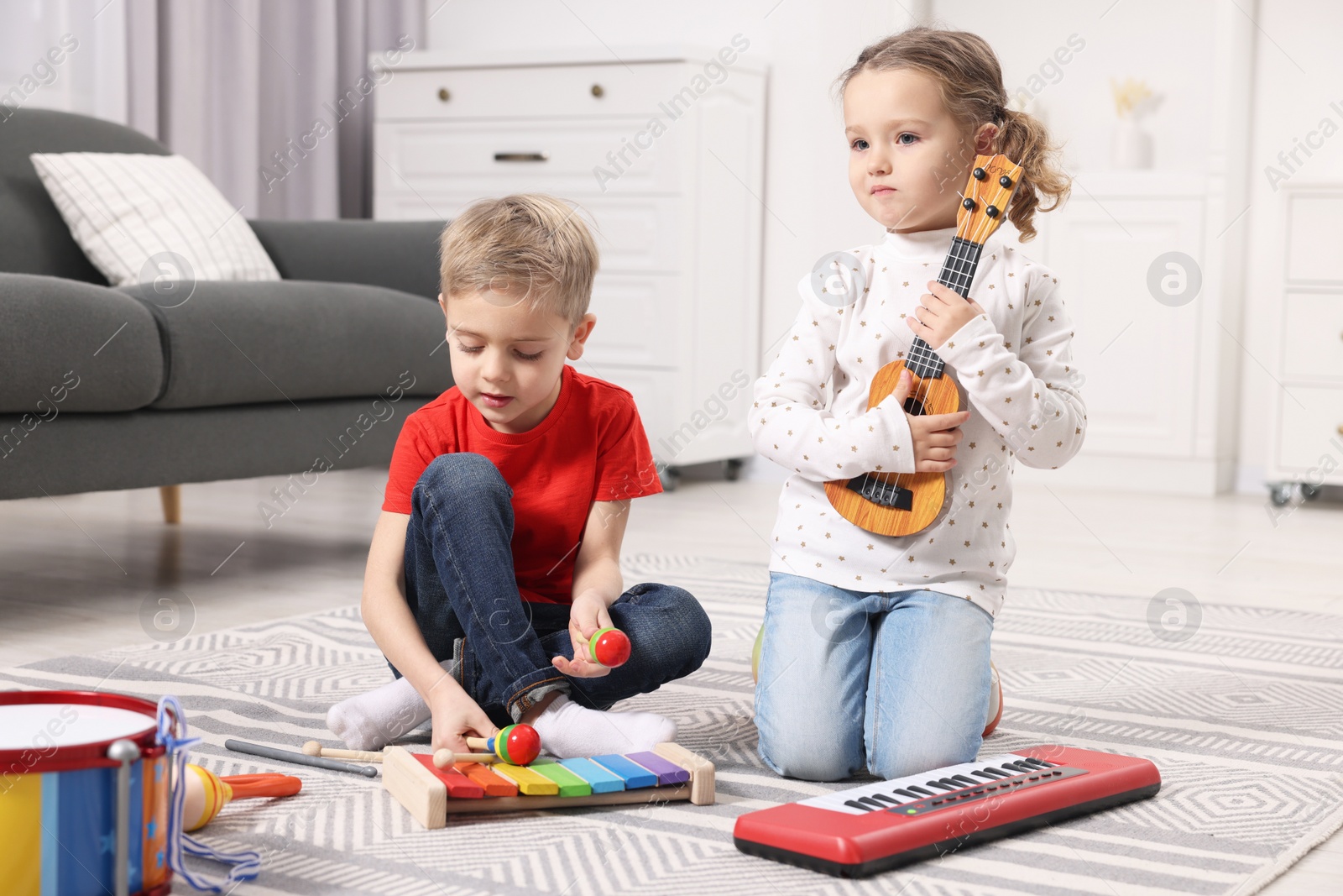 Photo of Little children playing toy musical instruments at home