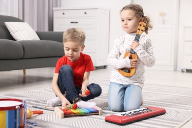 Photo of Little children playing toy musical instruments at home