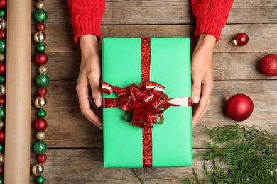 Woman wrapping Christmas gift at wooden table, top view