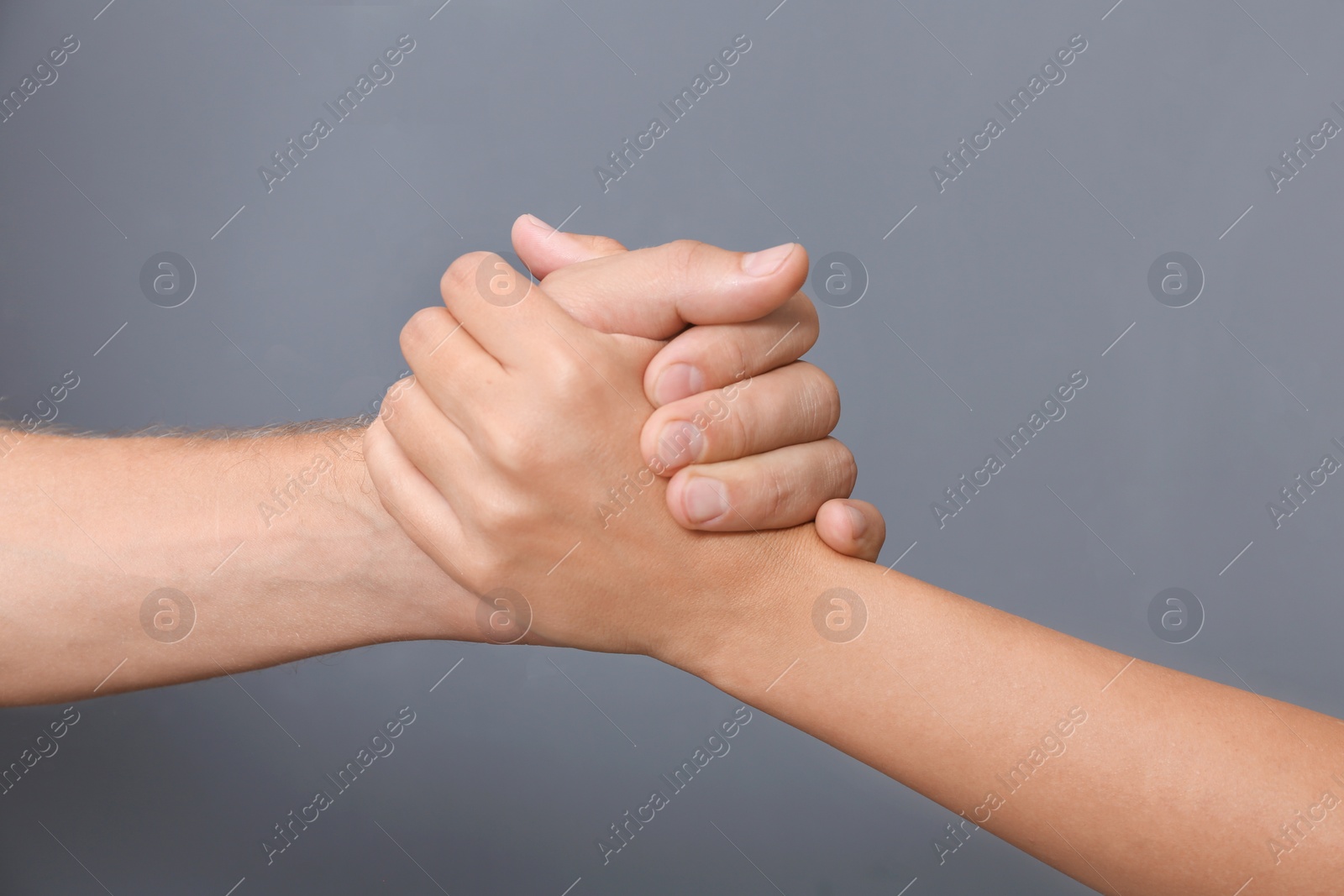 Photo of People holding hands together on gray background, closeup. Concept of support and help