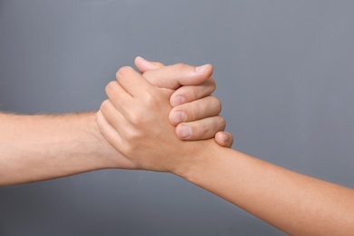 People holding hands together on gray background, closeup. Concept of support and help