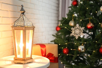 Photo of Beautiful lantern on table in room decorated for Christmas, space for text. Stylish interior element
