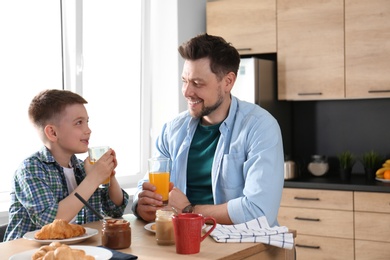 Dad and son having breakfast together in kitchen