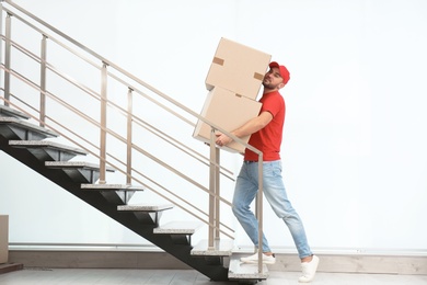 Man in uniform carrying carton boxes upstairs indoors. Posture concept