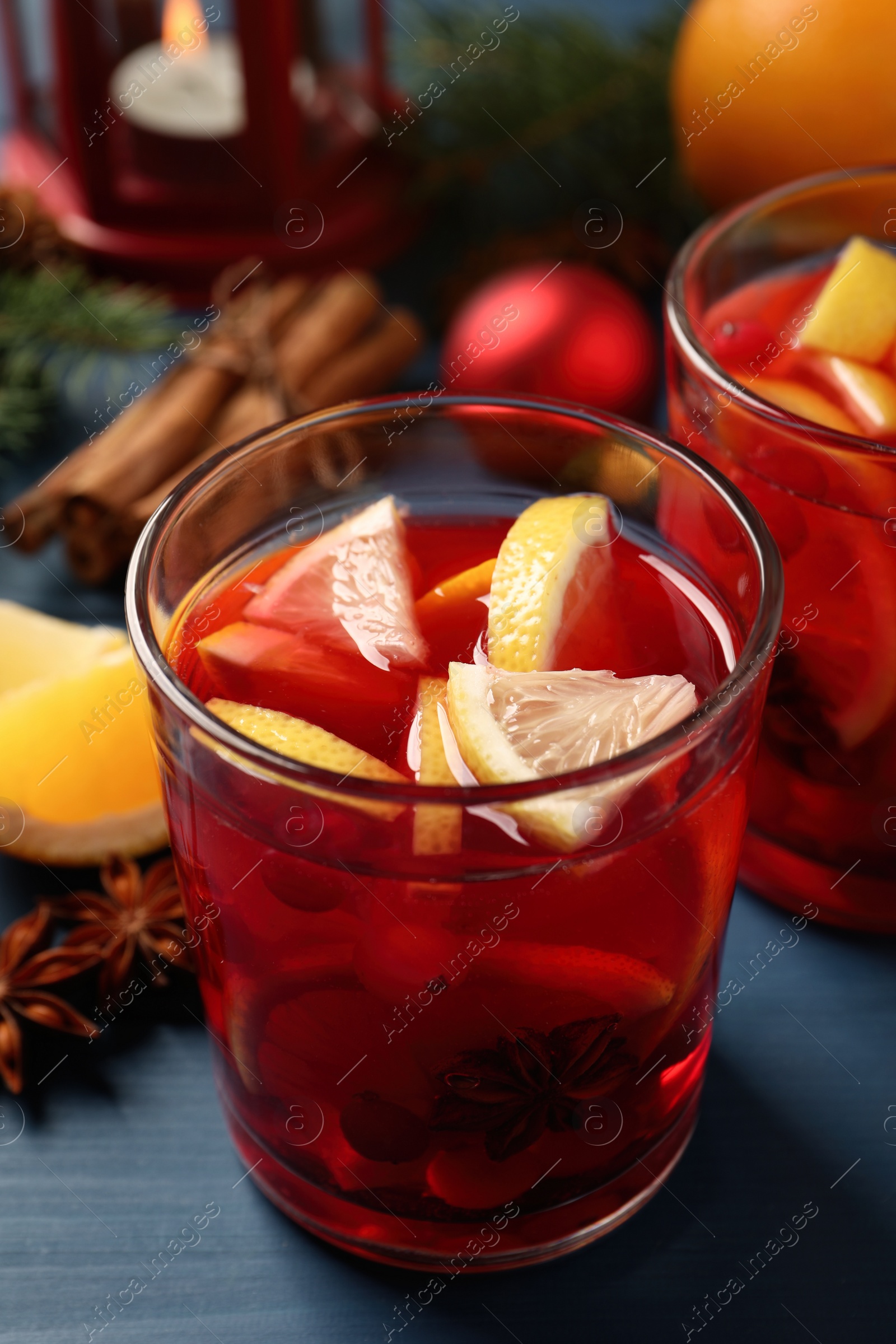 Photo of Delicious punch drink with cranberries and orange on blue wooden table