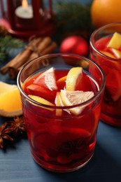 Photo of Delicious punch drink with cranberries and orange on blue wooden table