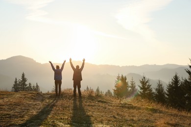 Photo of Couple enjoying sunrise in mountains, back view. Space for text