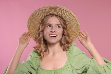 Portrait of beautiful woman with blonde hair in hat on pink background