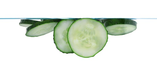 Photo of Slices of fresh cucumbers in glass with water on white background, closeup